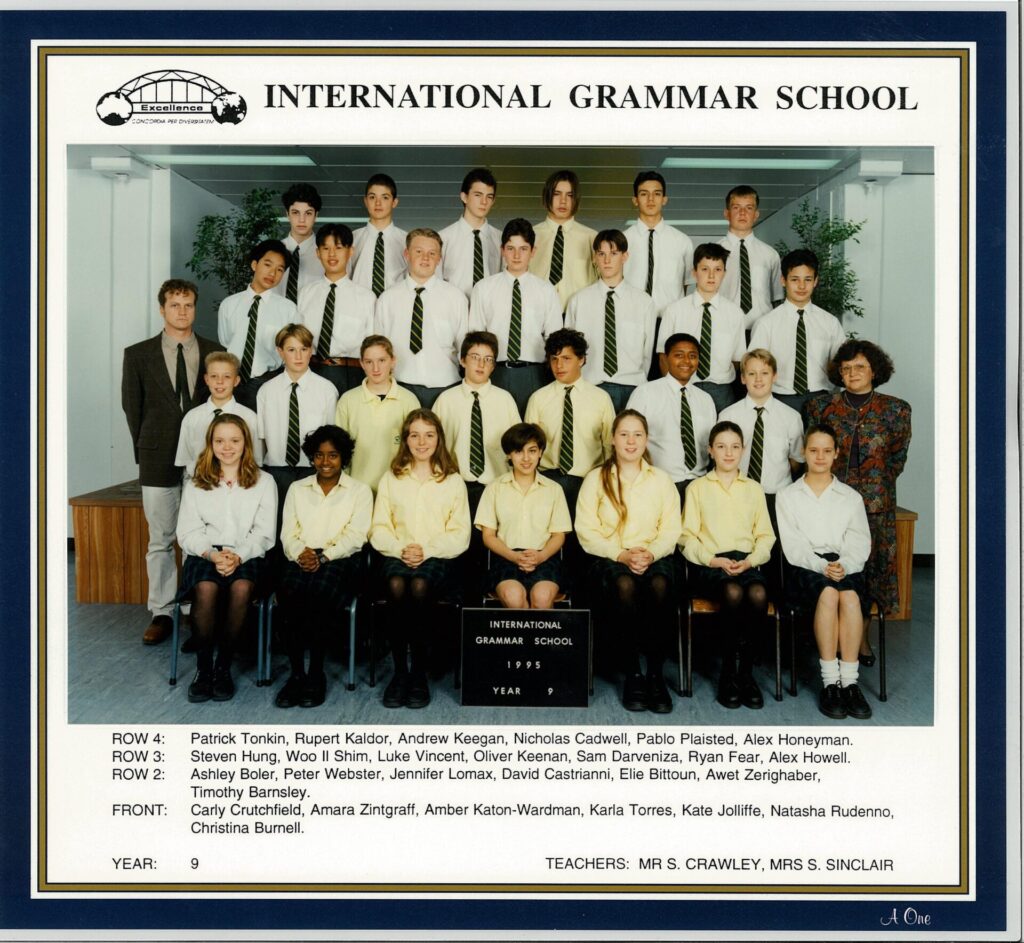 Class photo of Year 9 pupils and two teachers at International Grammar School in 1995. Pupils are in uniform, seated and standing in rows. Names of all individuals are listed below the photo.